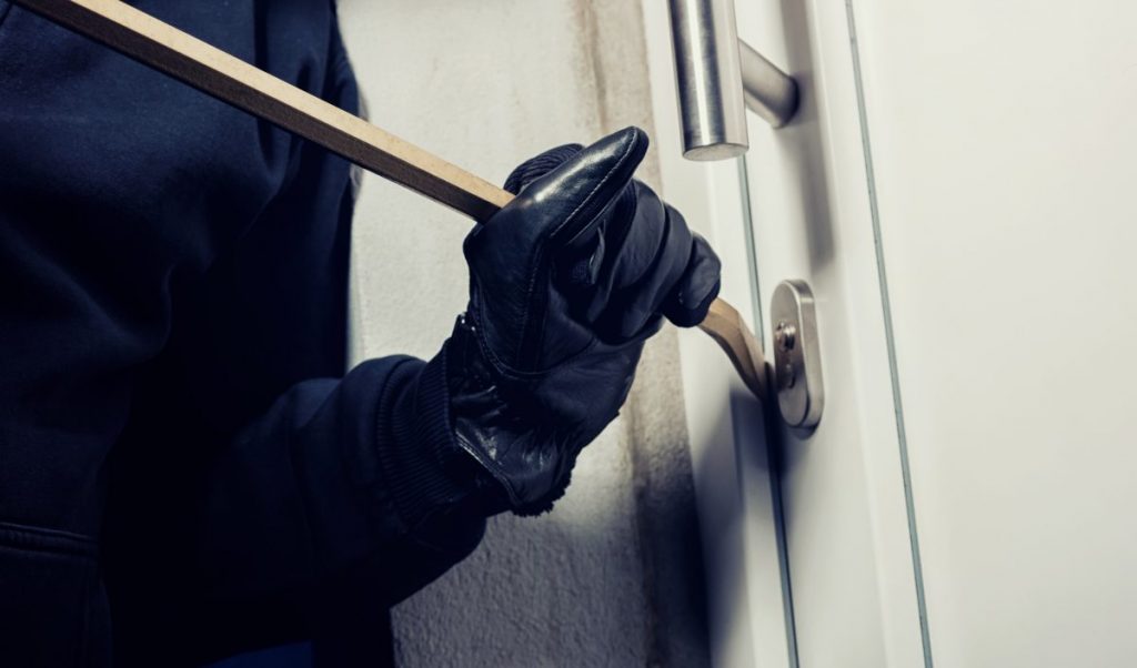 homme forçant une porte d'entrée avec un pied de biche