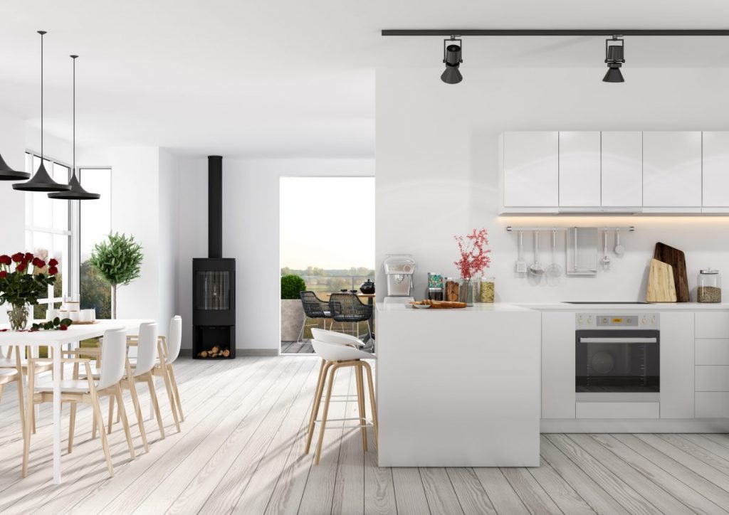séjour avec cuisine ouverte blanche salle a manger blanche et poêle a bois noir dans appartement en rez-de-chaussée
