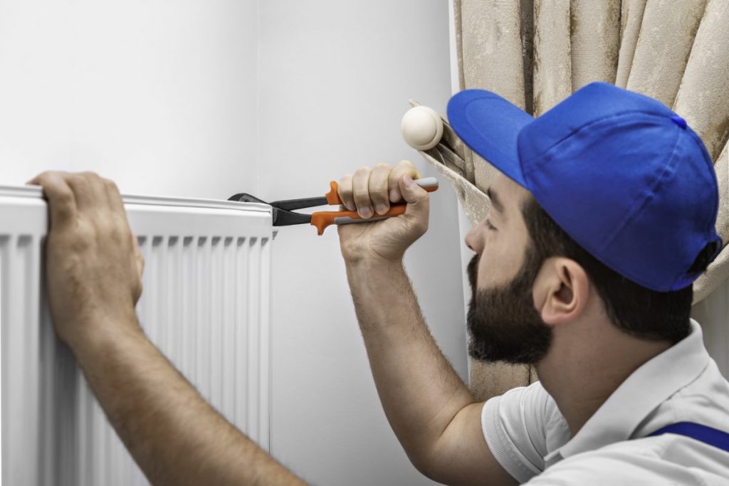 plombier réparant un radiateur blanc