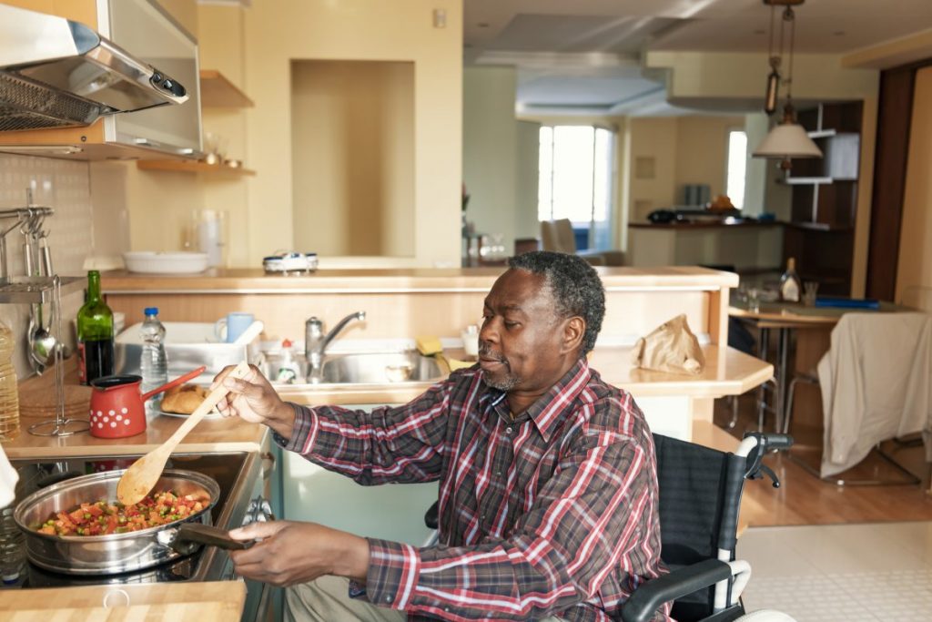 homme handicapé en train de cuisiner dans son logement adapté