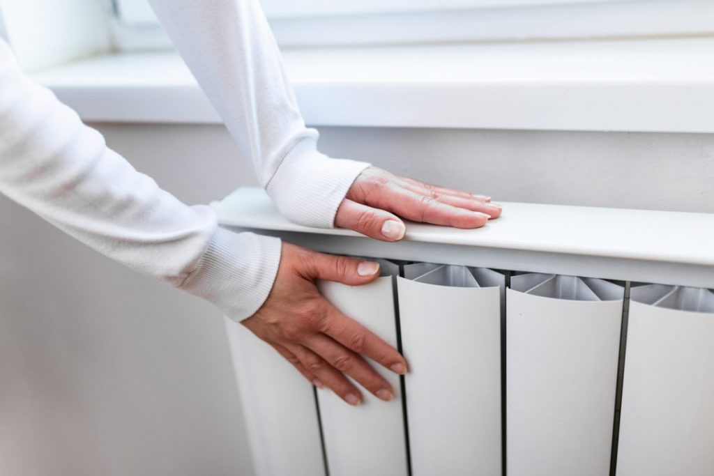 deux mains se rechauffent sur radiateur electrique