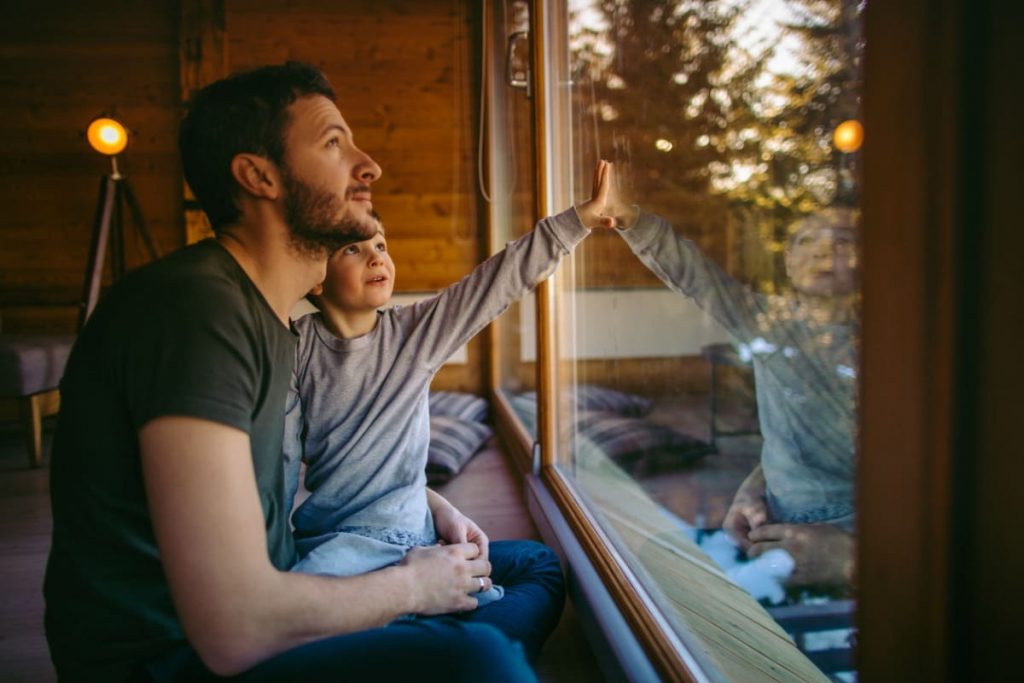 jeune papa avec son enfant devant fenetre
