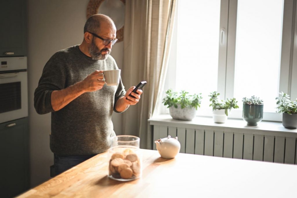 homme consulte smartphone dans cuisine