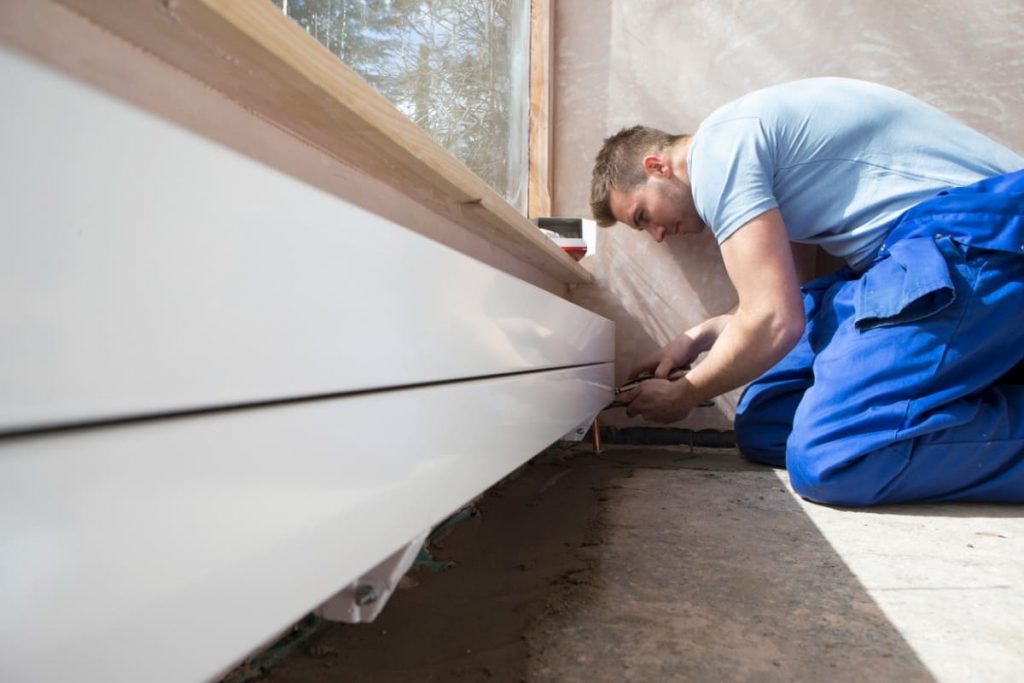 artisan installe radiateur plinthe sous fenetre