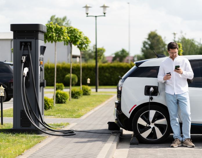 homme attend recharge de son vehicule electrique a la station de recharge