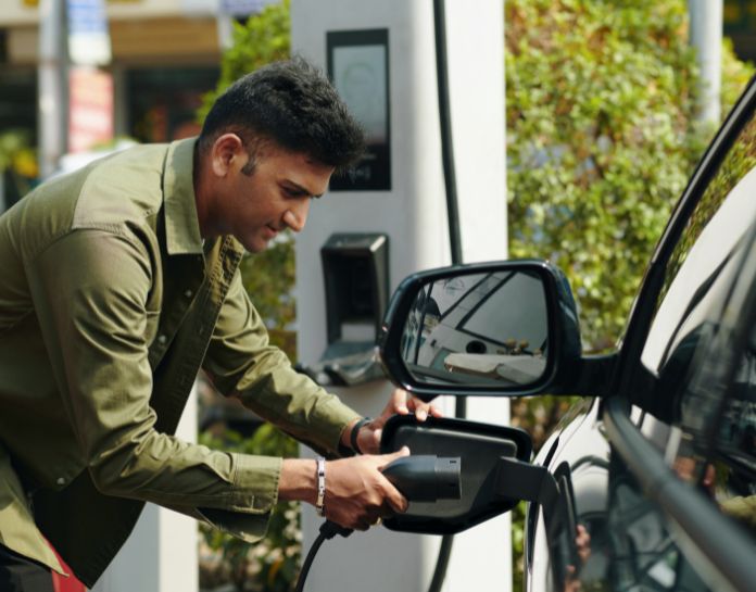 homme branche cable de recharge voiture electrique sur borne publique